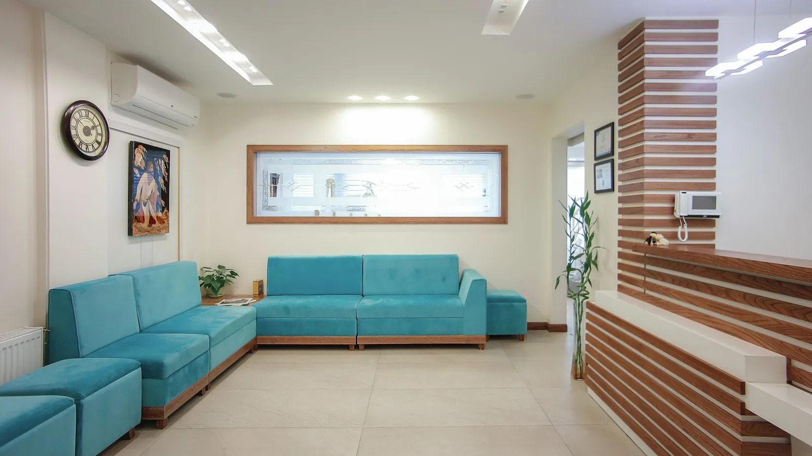 Sala de espera de clínica médica com sofás em tom verde, ambiente organizado e iluminado